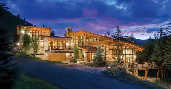 Large modern home with a stone-and-timber frontage at dusk