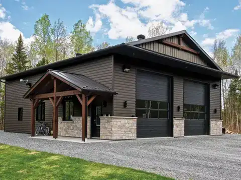 Post-frame shop with a timber entry porch, stone base and two overhead doors