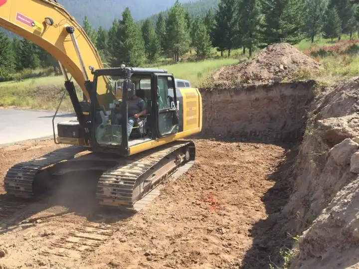 Excavator cutting a foundation pad on a cleared lot