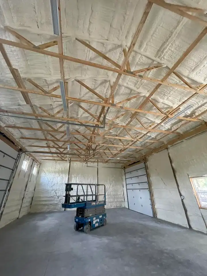Framed room with foil-faced insulation going in, a lift in the corner