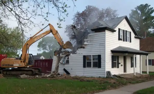 Excavator taking down a house
